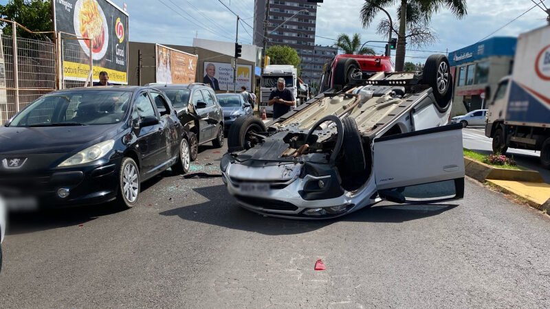 Carro atinge veículos estacionados e capota em avenida